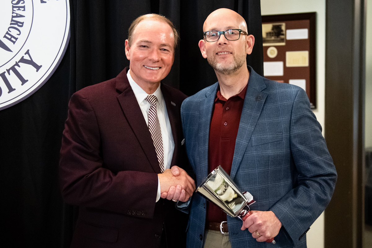 MSU President Mark E. Keenum presents a cowbell to retiring Vice President for Finance and Administration Don Zant.