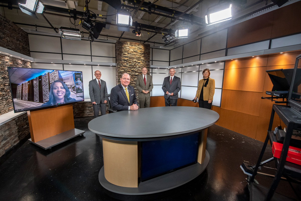 President Keenum sits at the TV Center's anchor desk, with USDA's Jacobs-Young on the screen, and four MSU VPs behind him.