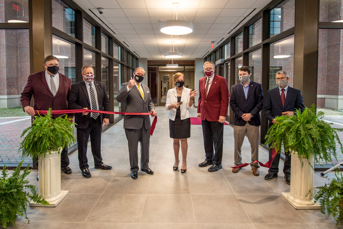 Seven dignataries celebrate cutting the ribbon across the glass hallway to the new Poultry Science Building.