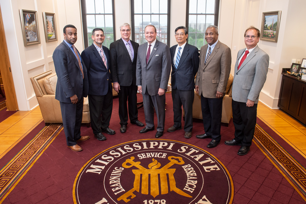 Group of six SDA Agricultural Research Service senior officials posed with President Keenum on MSU Seal rug.