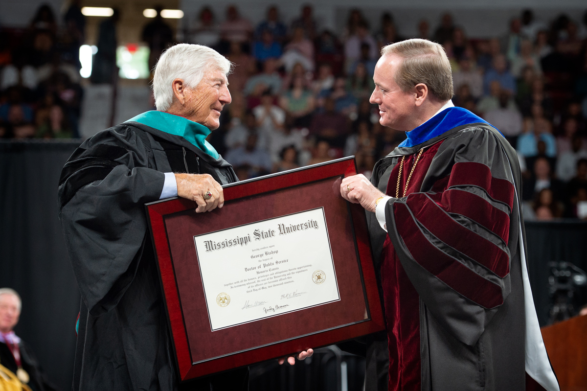 Alumni George Bishop receives his framed honorary degree from President Keenum on the Hump's Commencement stage.