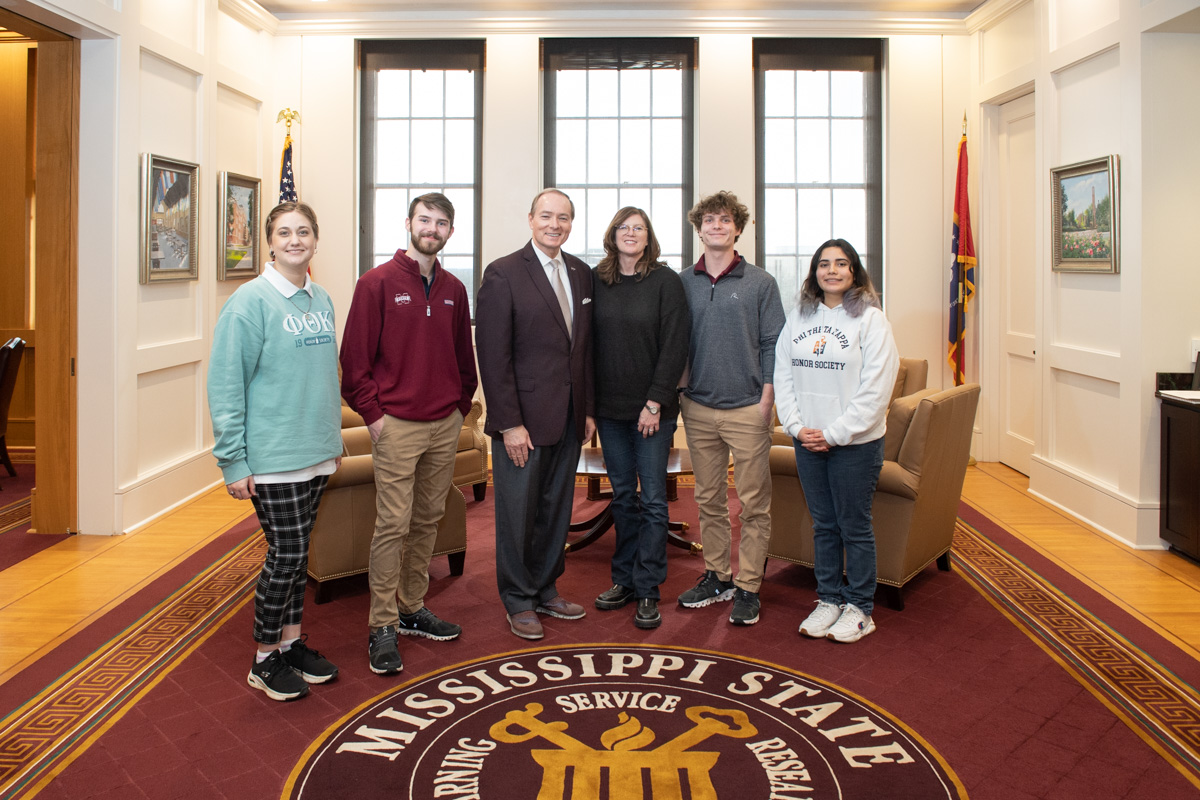 Five visiting Phi Theta Kappa Mississippi/Louisiana Region officers stand on either side of President Keenum.