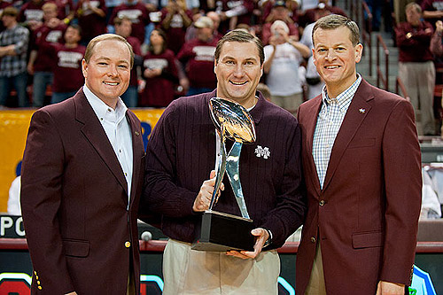 President Mark E. Keenum, from left, Head Football Coach Dan Mullen and Athletic Director Scott Stricklin display the Gator Bowl trophy during a home basketball game.
