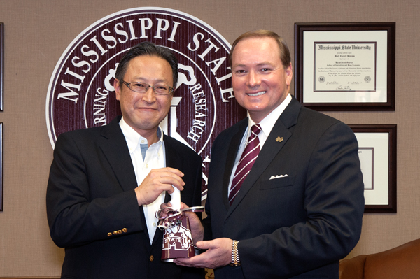 Dr. Mark E. Keenum, right, presents a cowbell as token of appreciation to Tadaharu Yamamoto, president of Yokohama Tire Manufacturing Mississippi, the new, West Point-based subsidary of Yokohama Tire Corp.