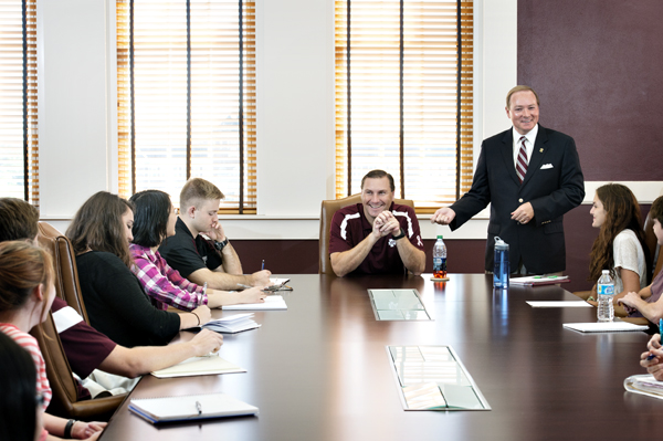 Mississippi State President Mark E. Keenum, standing, introduces head football coach Dan Mullen, center, to the honors leadership class.
