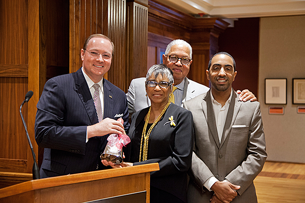 MSU President Mark E. Keenum, left, presents Shirley Kinsey, her husband Bernard, and son Khalil, right, with a chrome cowbell during the March 20 ribbon cutting ceremony for The Kinsey Collection’s “African American Treasures” exhibit at the unive