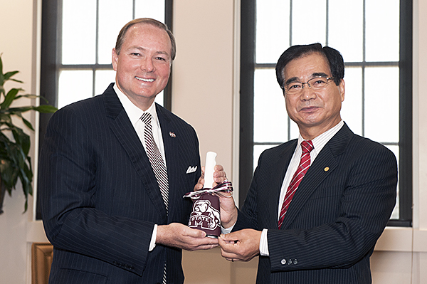 MSU President Mark E. Keenum, left, presents a maroon cowbell to Nihon University's College of Industrial Technology Dean Minoru Ochiai after the two leaders signed a memorandum of understanding Tuesday.