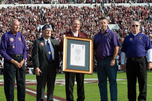 MSU President Mark E. Keenum, center, accepts the “Purple Heart University” designation on behalf of the university from Purple Heart veterans (l-r) Charles Sciple, Will Woods, Dennis “Denny” Daniels Jr.