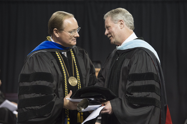 MSU President Mark E. Keenum, left, gives Glenn F. Boyce a cowbell after the commencement address May 7.