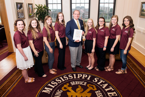 Mississippi State’s inaugural James Patterson Teacher Education Scholars present a “Helping Hands of Friendship” book to MSU President Mark E. Keenum on Monday [Aug.