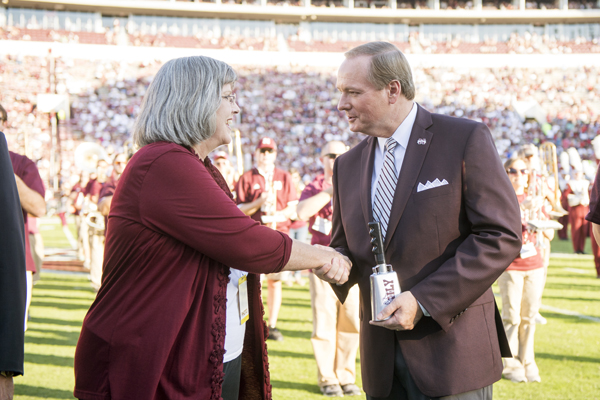 Mississippi State University President Mark E. Keenum presents a cowbell to MSU Director of Bands Elva Kaye Lance during halftime of Saturday’s [Oct.