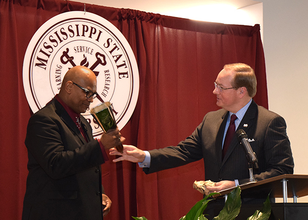 MSU President Mark E. Keenum, right, presents a cowbell to Oktibbeha County Justice Court Judge Larnzy L. Carpenter Jr., who served as the keynote speaker to an overflow crowd at Mississippi State University during the 23rd annual Martin Luther King Jr.
