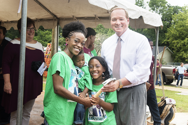 MSU President Mark E. Keenum, right, presents a hammer to Habitat for Humanity partner family Kareema Gillon and her two children.