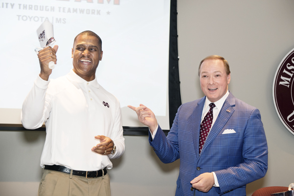 Mississippi State University President Mark E. Keenum presents a cowbell to Toyota Motor Manufacturing Mississippi Inc.