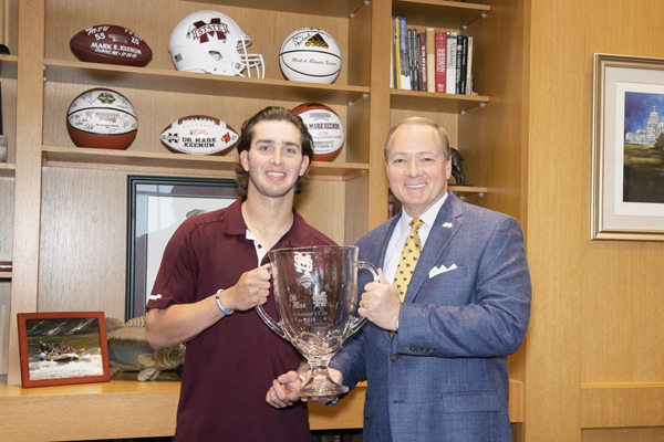Mississippi State shortstop Luke Alexander presents MSU President Mark E. Keenum with the 2018 Governor’s Cup trophy.