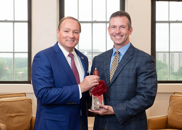 MSU President Mark E. Keenum, left, presents a commemorative cowbell to Dr. Brent Fountain, Associate Extension Professor in the Department of Food Science, Nutrition, and Health Promotion, in recognition of Fountain service of President of MSU’s Holla
