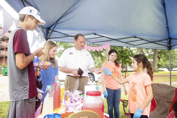 MSU President Mark E. Keenum purchases lemonade for himself and two of his children from the “Lemony Spickets” stand