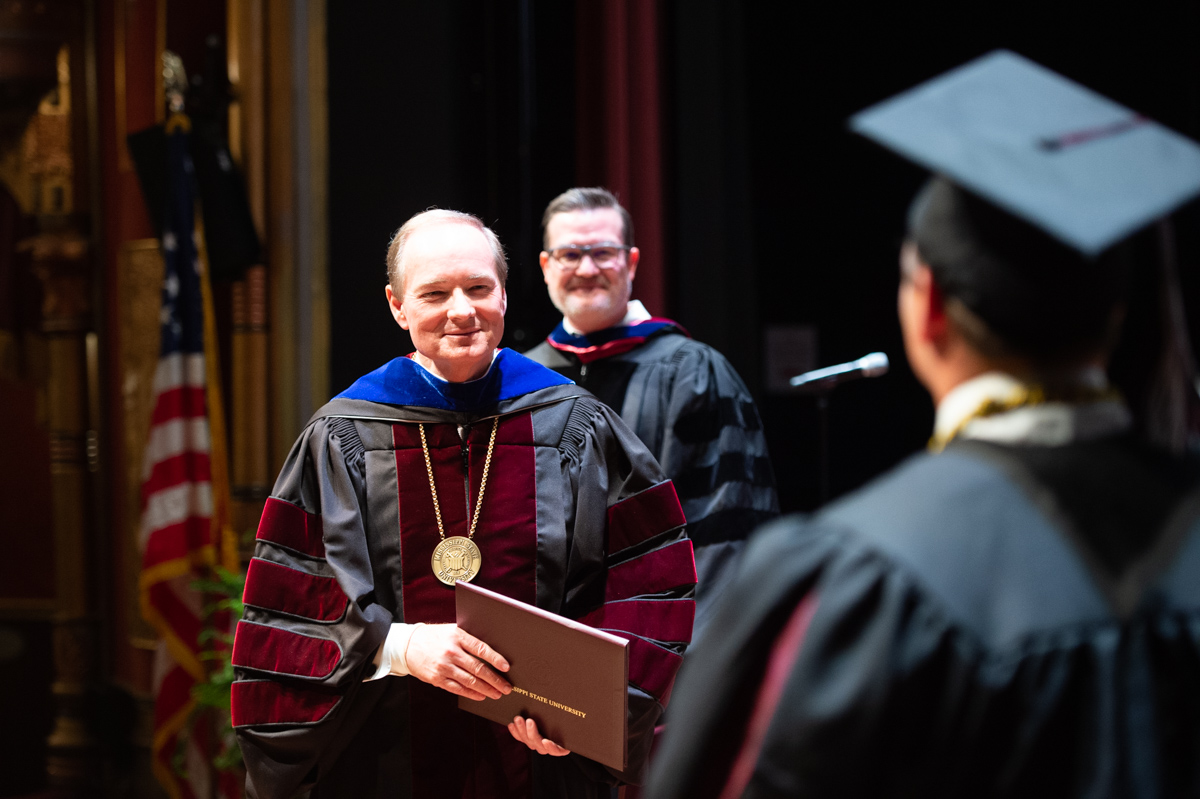 9.)	Mississippi State President Mark E. Keenum smiles with pride as a student participating in MSU-Meridian’s spring commencemen