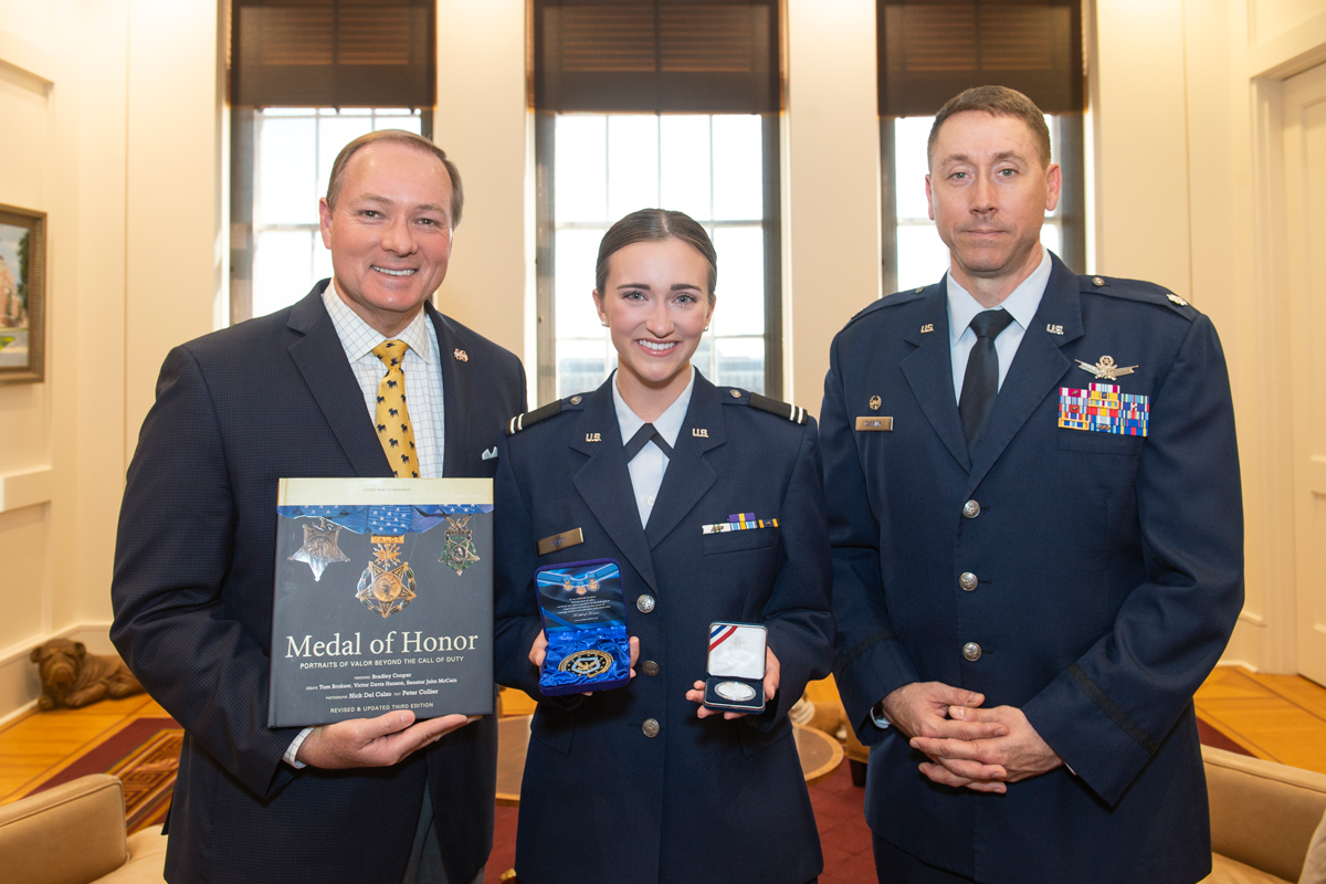 MSU Air Force ROTC Cadet Shelby Patti holds her Medal of Honor medals, standing between President Keenum and Lt. Col. Cassidy.