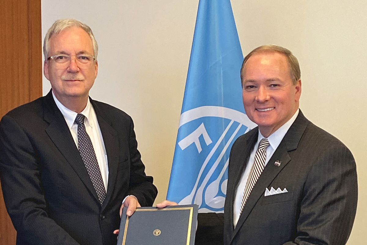FAO  Deputy Director-General for Programmes Daniel Gustafson (left) with President Keenum, in front of FAO flag.