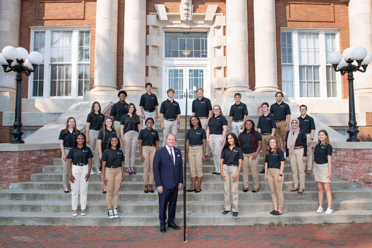 Dressed in black shirts and khaki trousers, the 2021-22 Presidential Scholars pose on Lee Hall's steps with President Keenum.