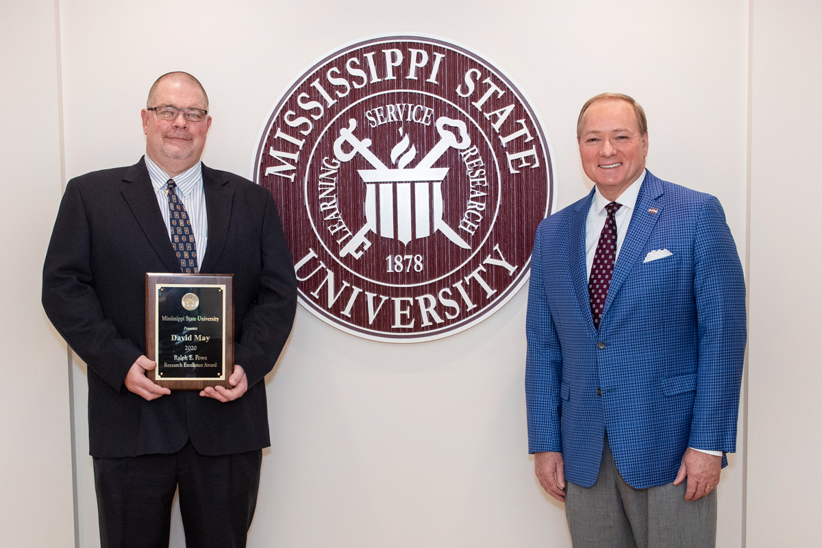 With the MSU seal between them, President Keenum stands to the right and David May stands to the left, holding his Powe award.