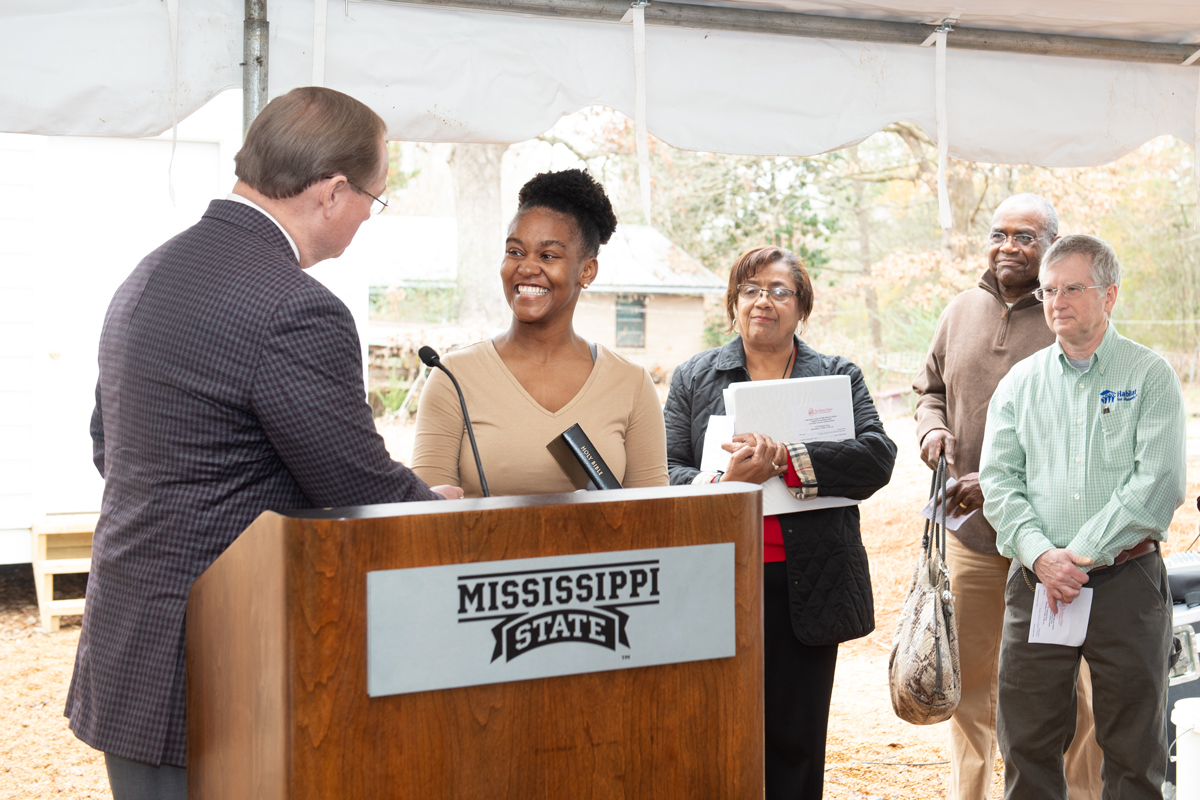 President Keenum presents a family Bible to Lou’Quan Lucious, homeowner of the 10th Maroon Edition Habitat home.