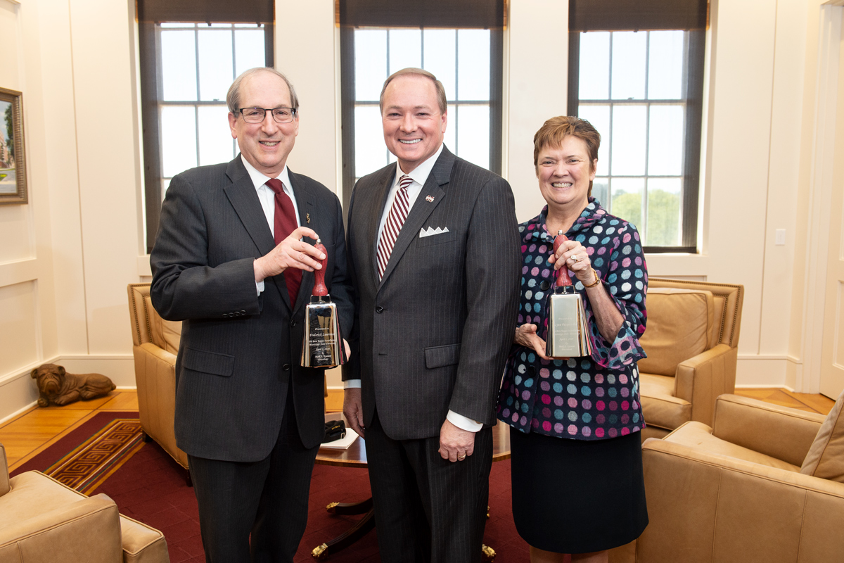 President Keenum stands with Phi Beta Kappa VIPs on either side holding cowbells.