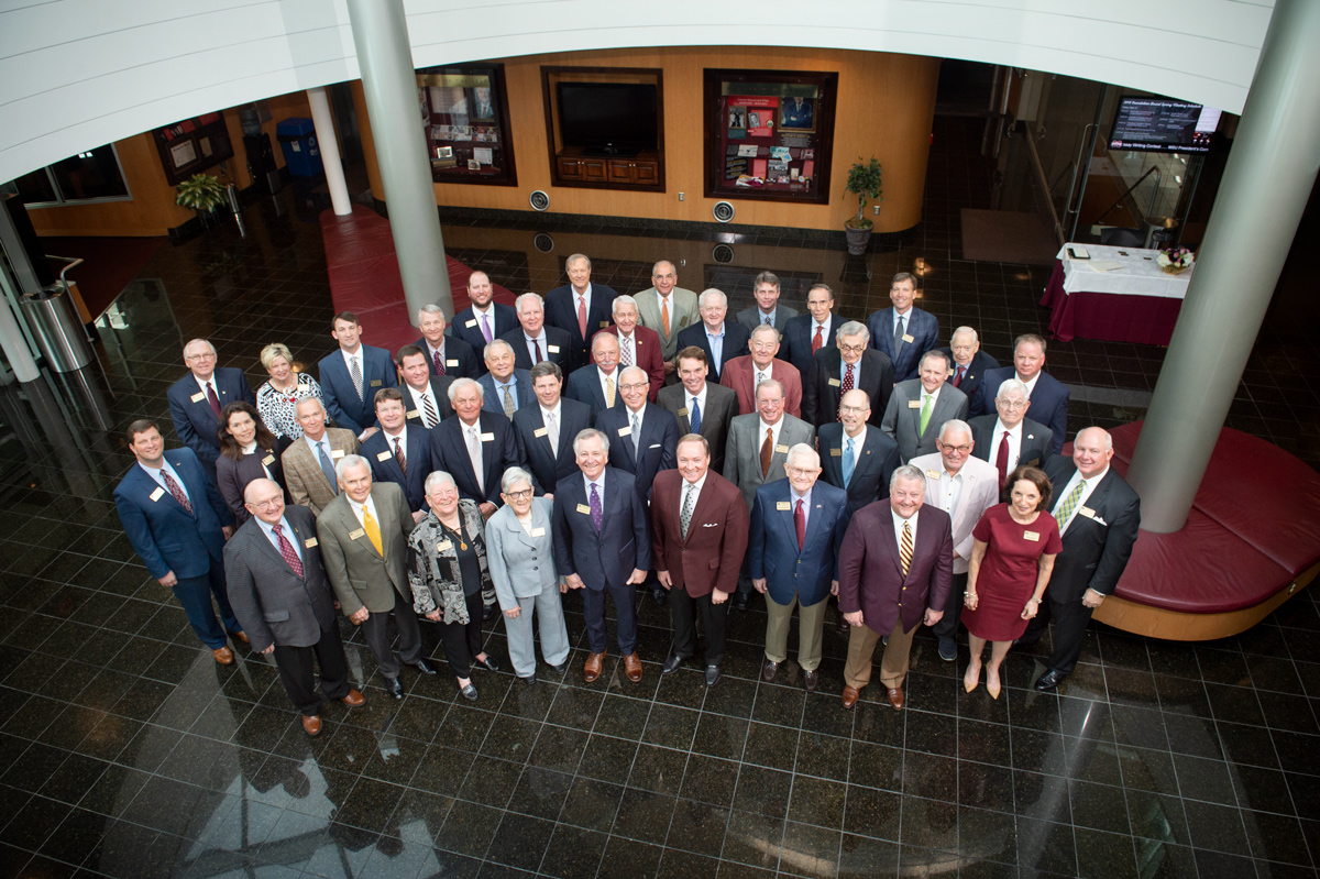 The MSU Foundation Board of Directors group stands posed together in the Hunter Henry atrium, looking up at the camera.