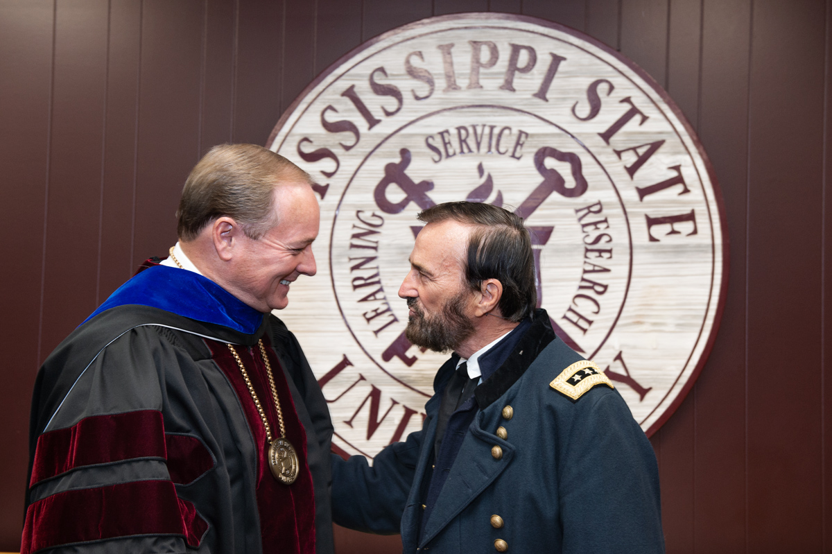 MSU President visits with US President Grant interpreter Curt Fields in front of the MSU Seal.