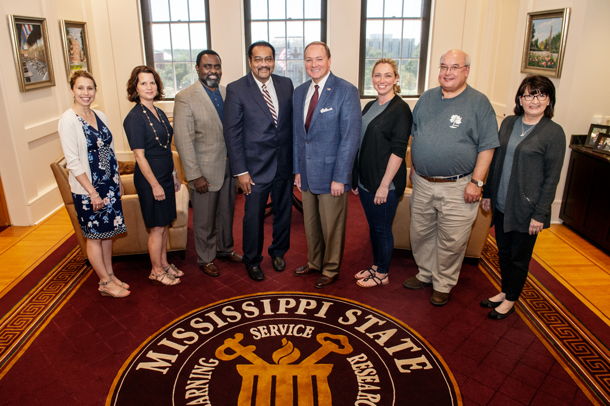 President Keenum poses in his office with seven guests involved in the Autism Transition Conference.