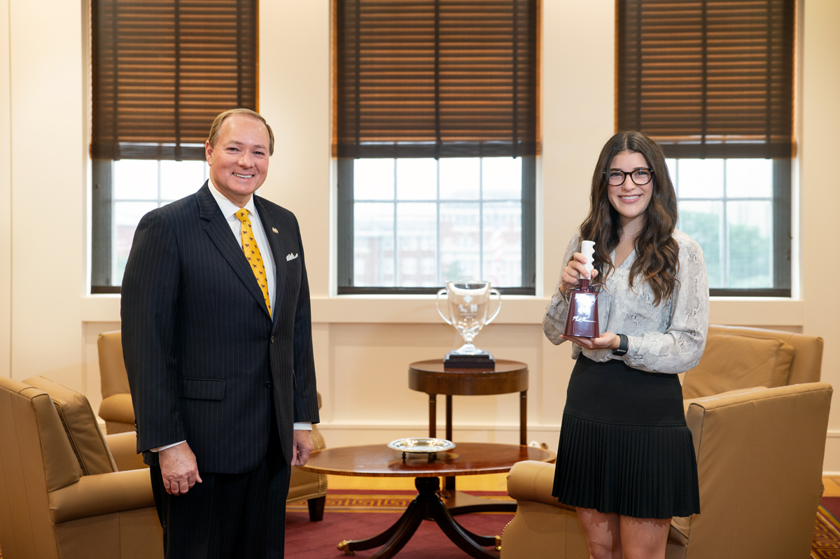 President Keenum stands in his office with kidney donor Reagan Scott, holding her gifted cowbell.