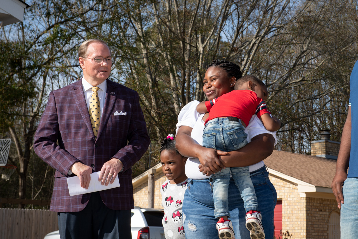President Keenum stands to the left of new Maroon Edition Home owner Keva Robertson, holding her son Laquante Gaston Jr.  