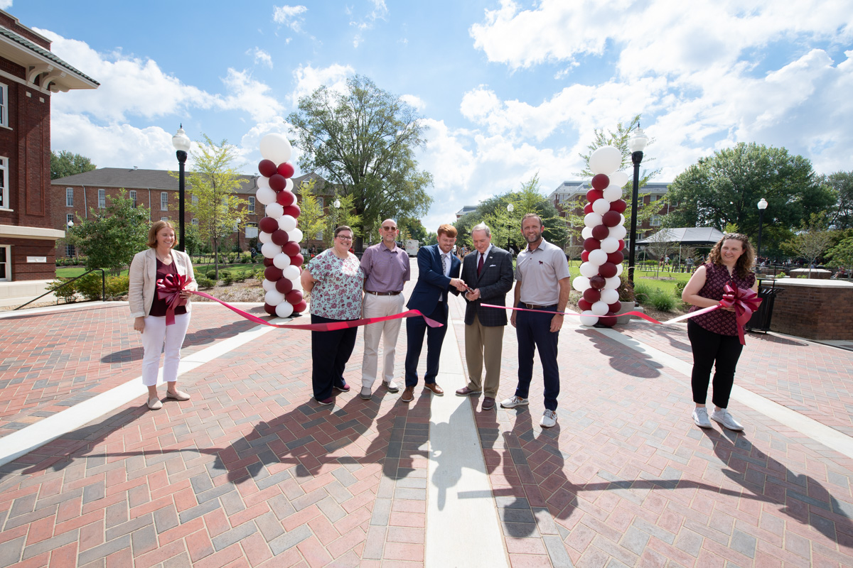 With SA President Guest and President Keenum at the center, VIPs cut the maroon ribbon crossing the new YMCA Plaza.