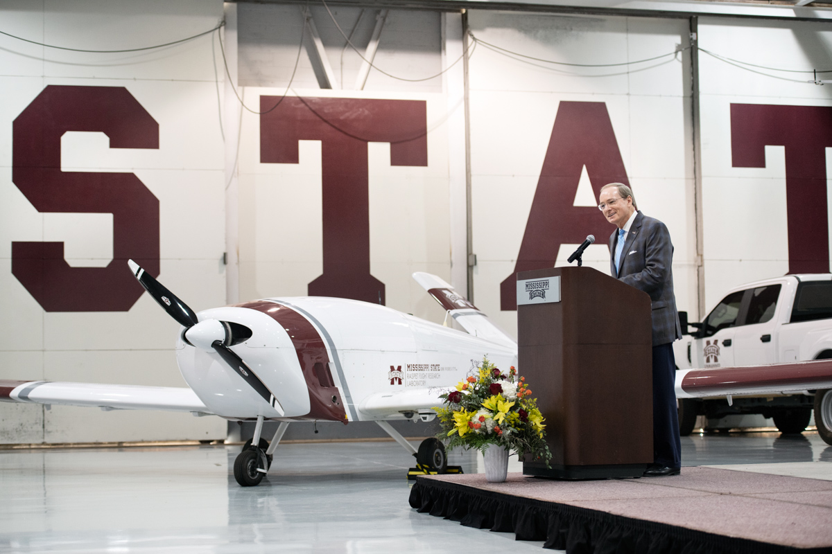 With the Teros UAS plane behind him in the Raspet hanger, President Keenum speaks from the podium during the unveling ceremony.