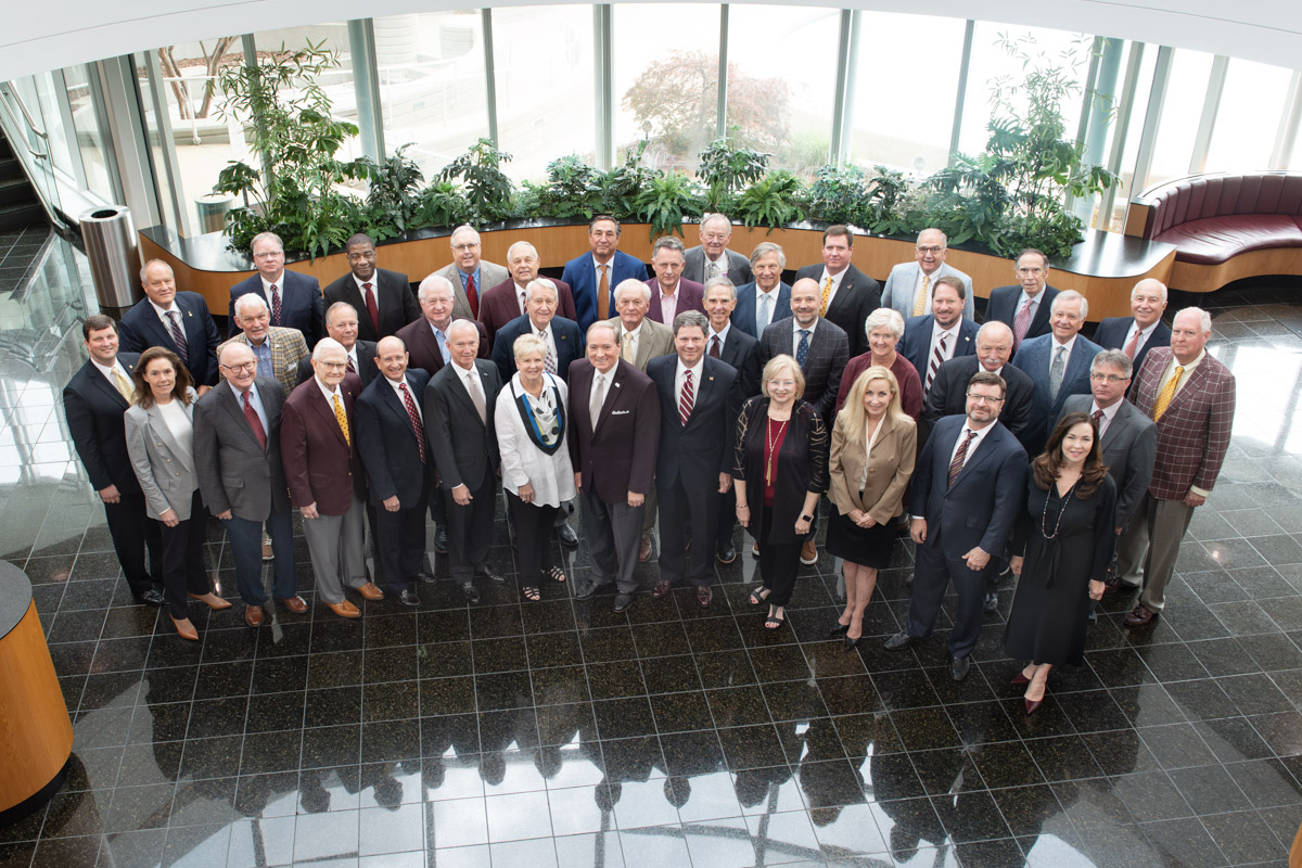 Group portrait of the Foundation Board, standing in the atrium of the Hunter Henry Center, looking up.