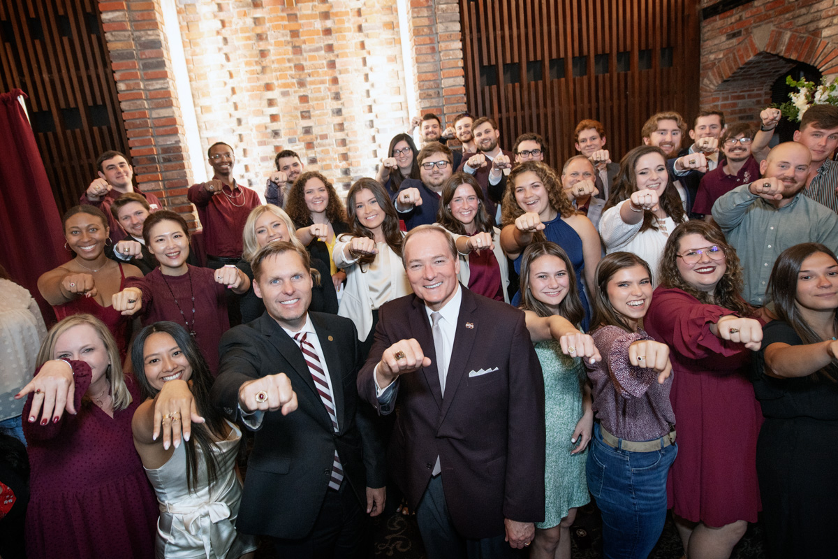 Congressman Guest and President Keenum at center, the crowd of Ring Ceremony participants hold their hands toward the camera.